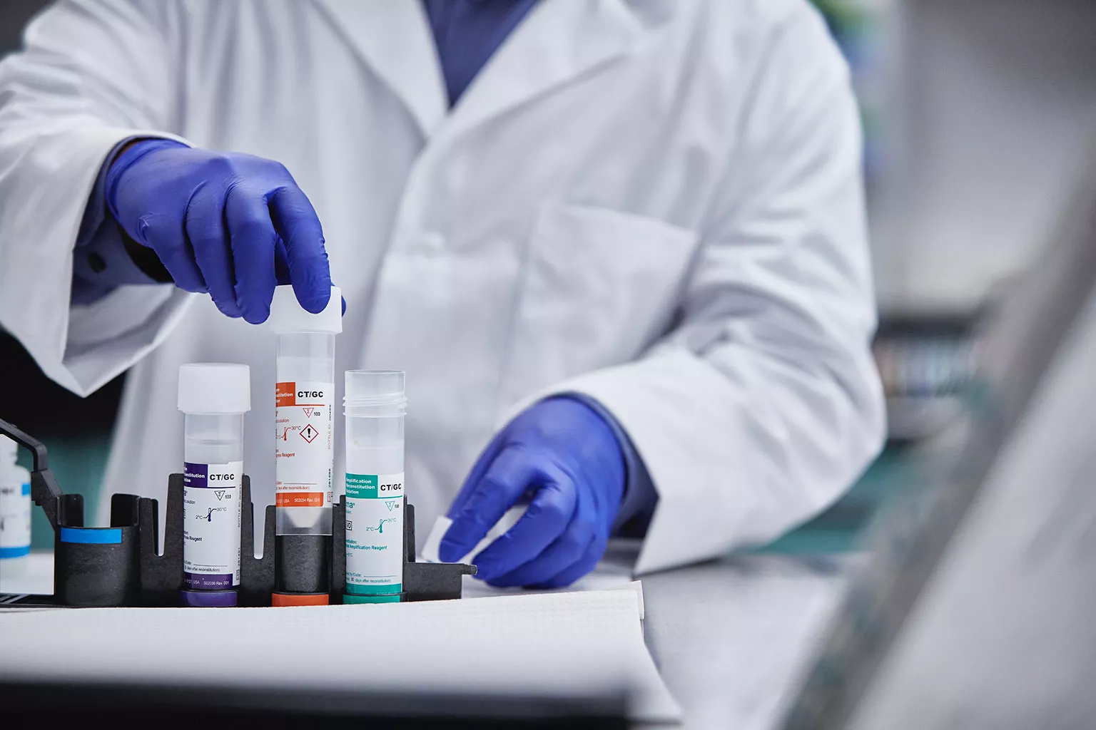 Técnico de laboratorio retirando tubos en un laboratorio.