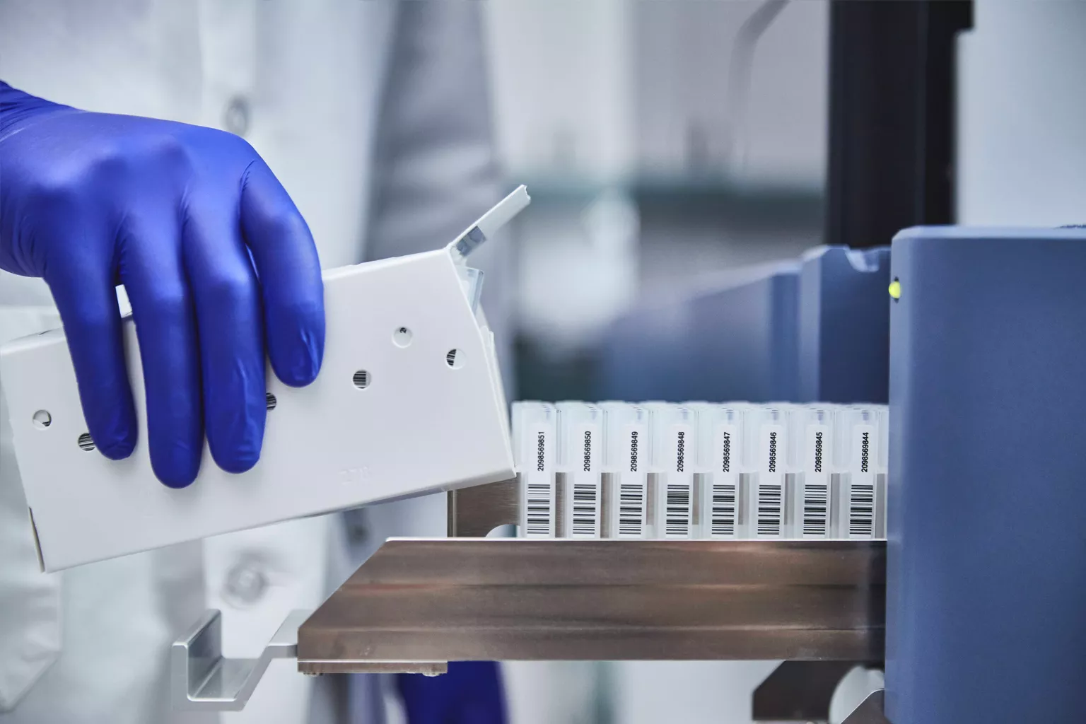 Técnico de laboratorio cargando una bandeja de tubos en un laboratorio.