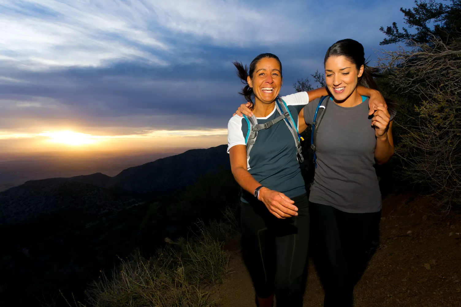 Dos mujeres caminando por la montaña al atardecer.