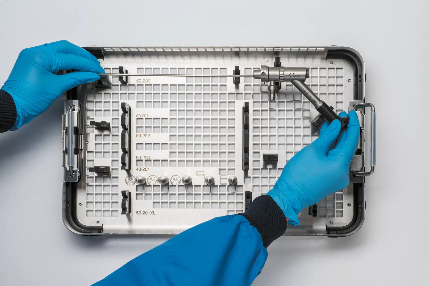 Manos con guantes trabajando con la bandeja médica sobre una mesa.