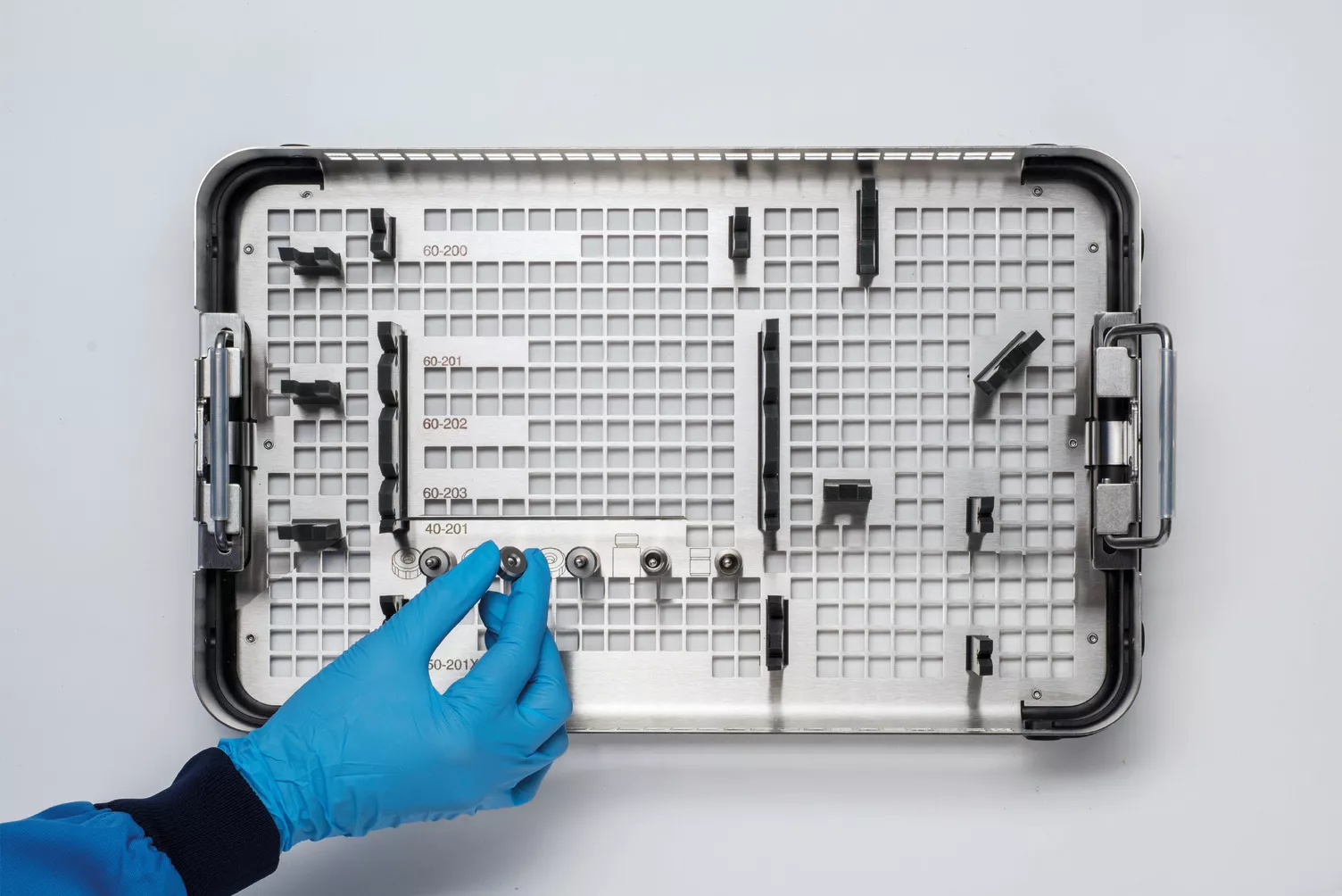 Mano con guante trabajando con la bandeja médica sobre una mesa.