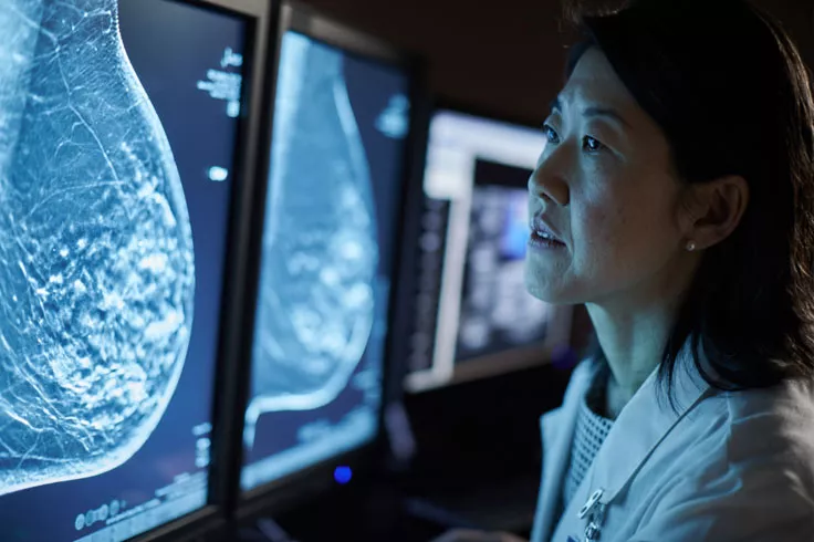 Profesional sanitario consultando mamografías en varias pantallas