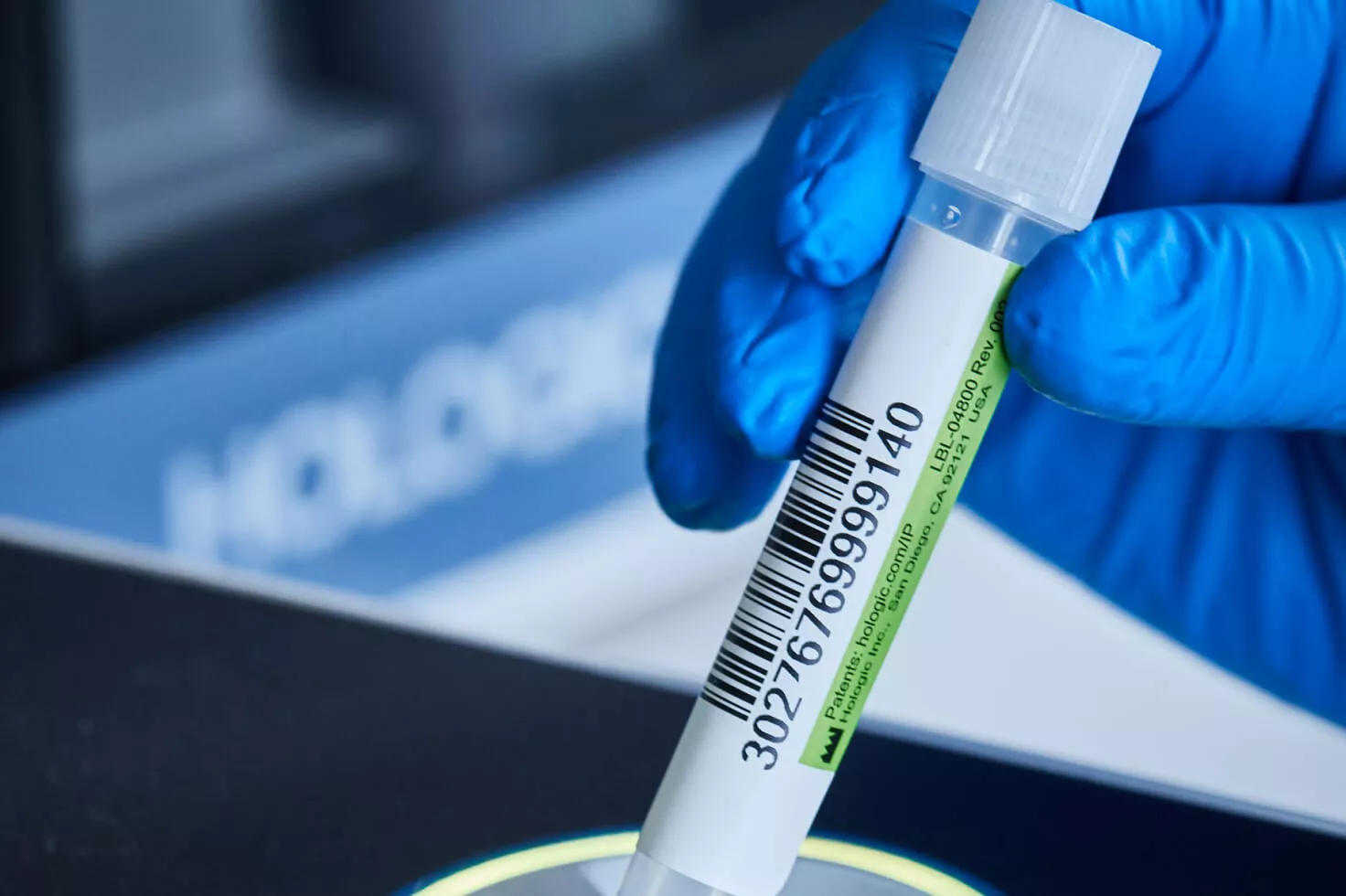 Primer plano de una mano con guante sosteniendo un vial